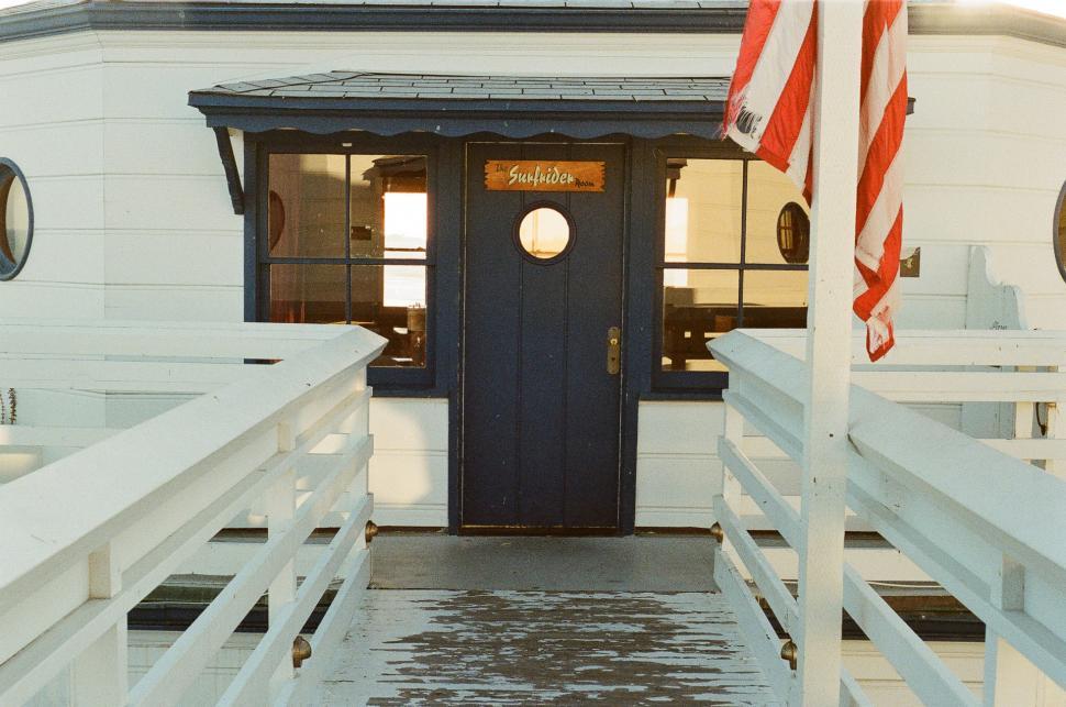Free Image of White Building With Blue Door and American Flags 
