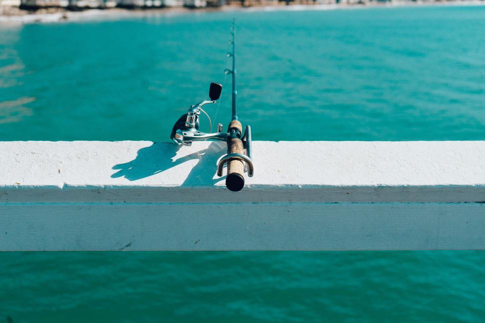 Free Image of Fishing Rod Resting on Edge of Pier 