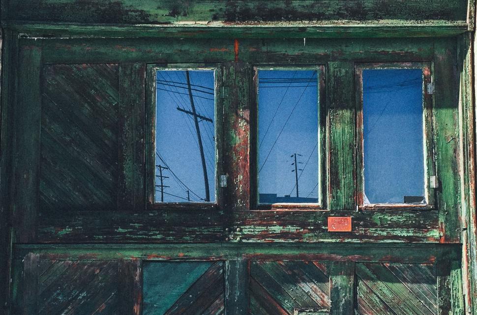 Free Image of A Painting of a Green Door With Three Windows 