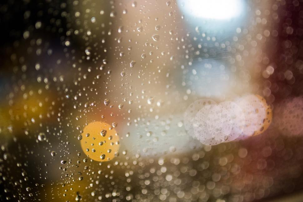 Free Image of Rain Covered Window With Street Light in Background 