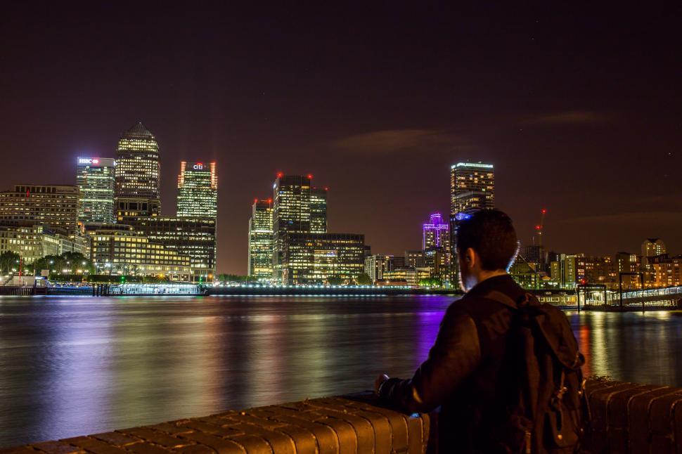 Free Image of Man Looking Out Over Water at City 
