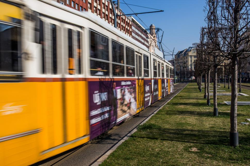 Free Image of Yellow and Purple Train Traveling Down Street 