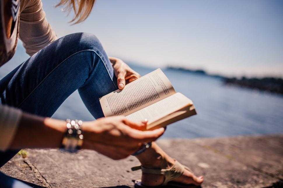 Free Image of Woman Sitting on Ledge Reading Book 