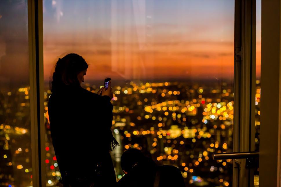 Free Image of Person Standing in Front of Window Looking at Cell Phone 