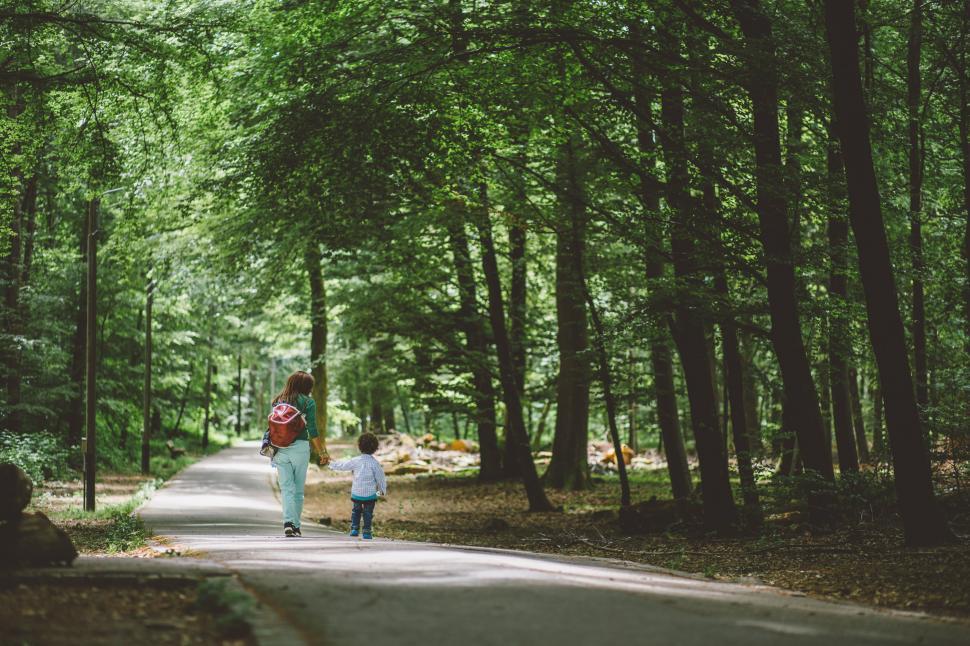 Free Image of Woman and Child Walking Down Tree Lined Road 