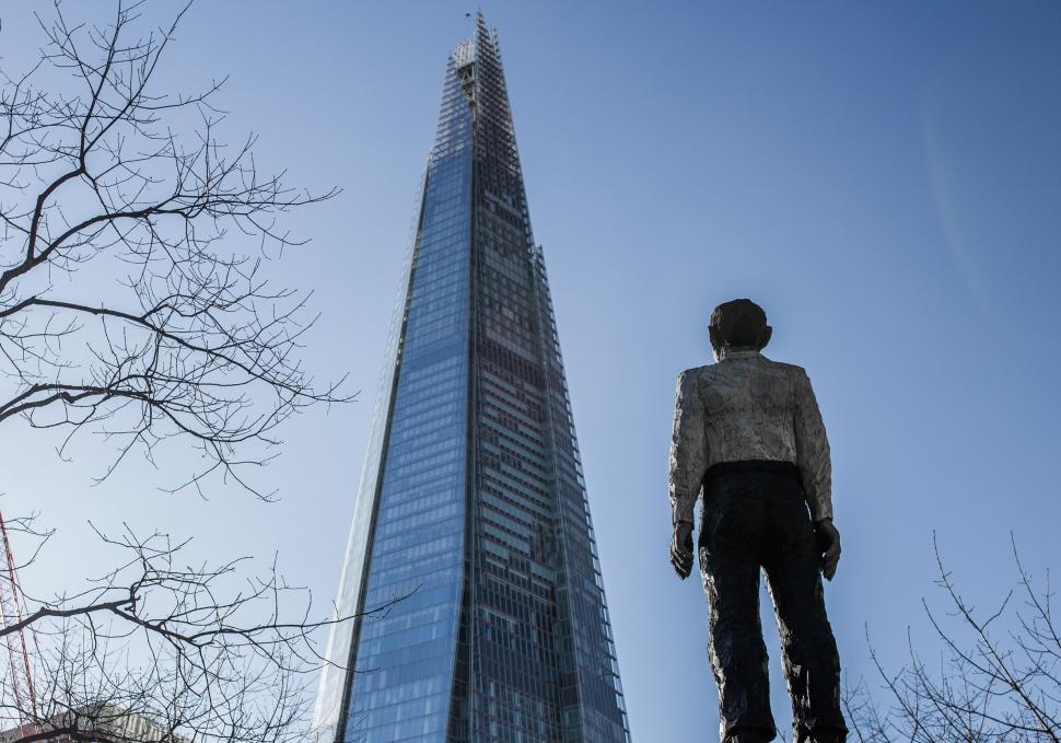 Free Image of Statue of a Man Standing in Front of a Tall Building 