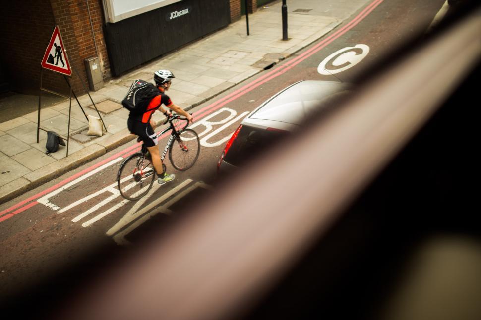 Free Image of Man Riding Bike Down Street Next to Traffic Light 