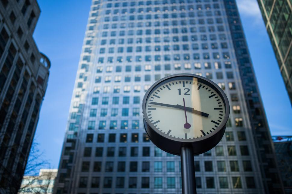 Free Image of Clock on Pole in Front of Tall Building 