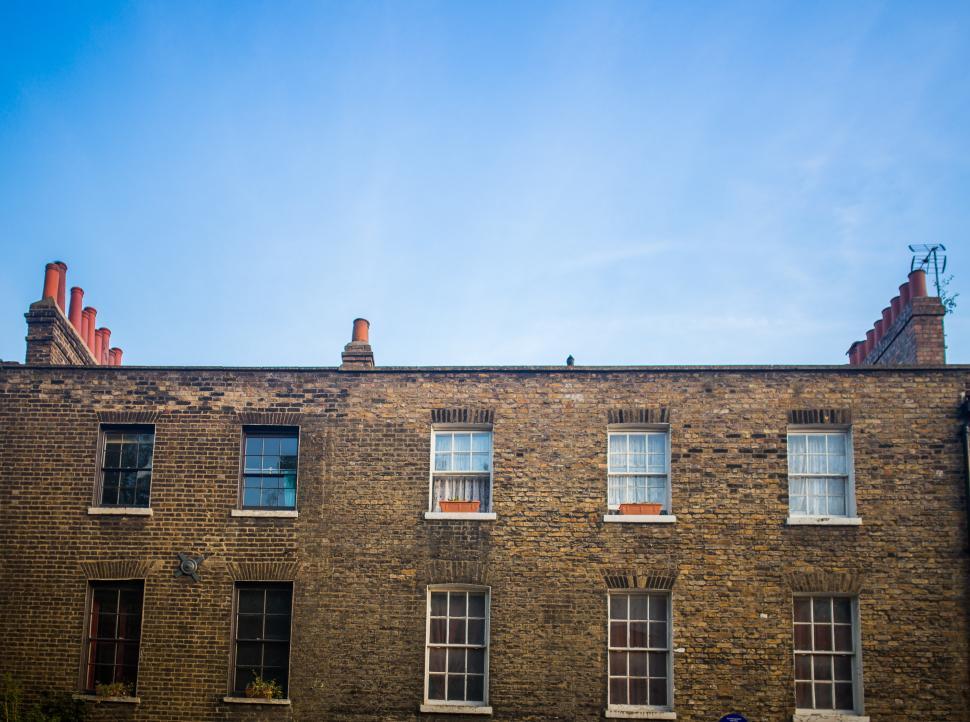 Free Image of Tall Brick Building With Windows Against Sky Background 
