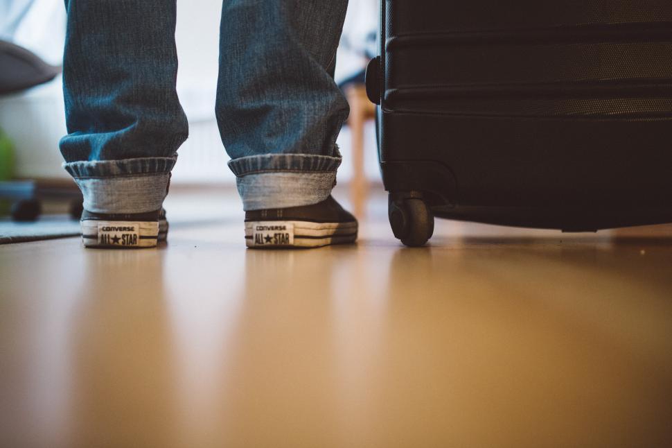 Free Image of Person Standing Next to Suitcase on Hardwood Floor 
