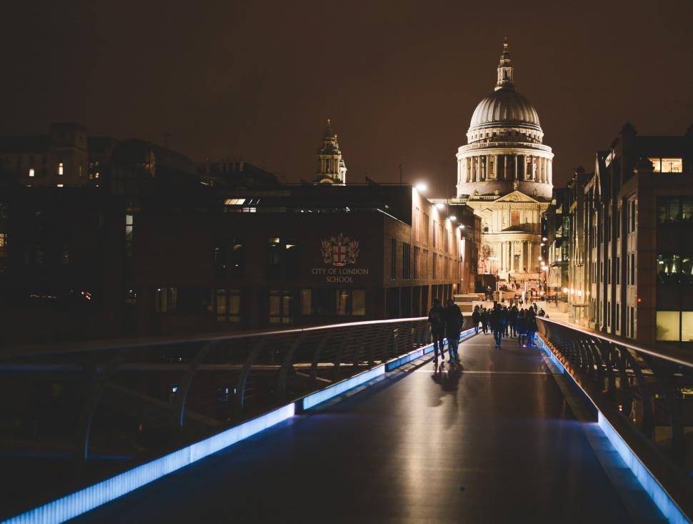 Free Image of People Walking Across Bridge at Night With Building in Background 