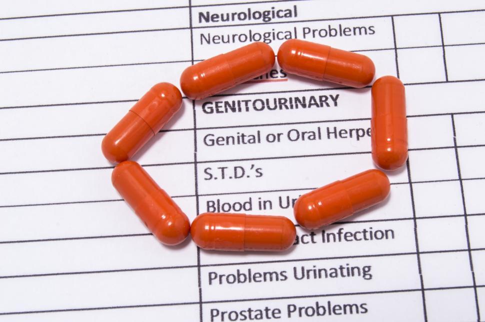 Download Free Stock Photo of Orange medical antibiotic capsules lie around the inscriptions genitourinary, herpes, STDs, problem urinating of medical history  