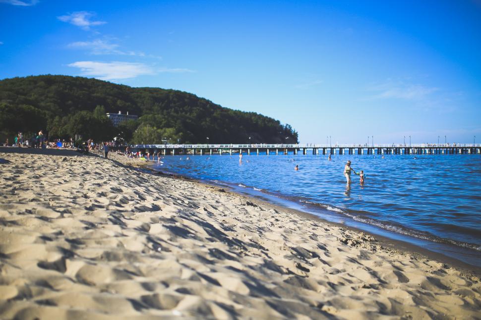 Free Image of Sand Beach With Pier in Background 