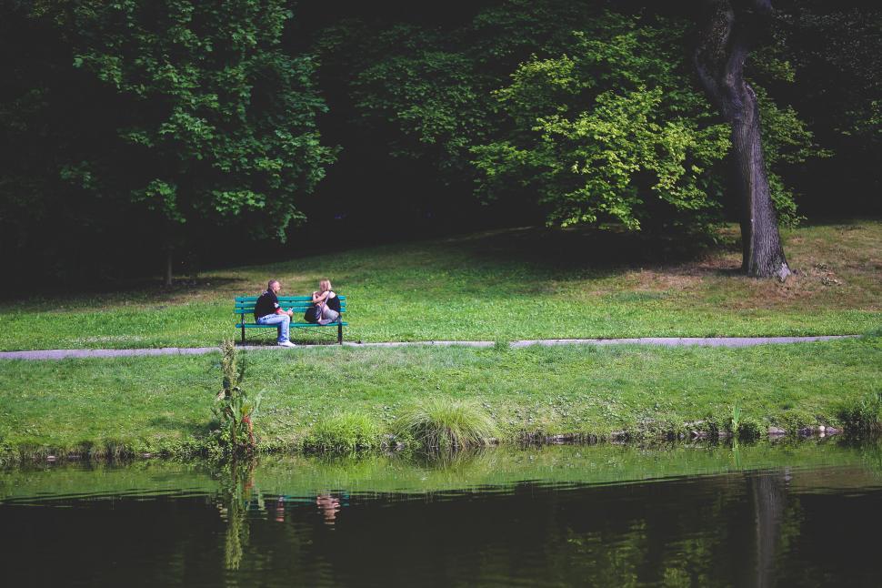 Free Image of Two People Sitting on a Bench by a Waterfront 