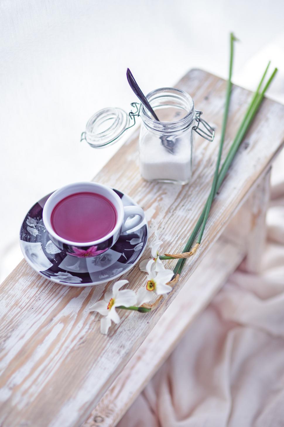 Free Image of Cup of Tea on Plate Next to Flowers 