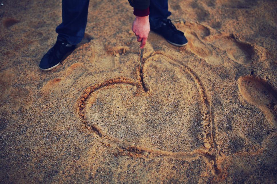 Free Image of Person Standing in the Sand With Heart Drawn 