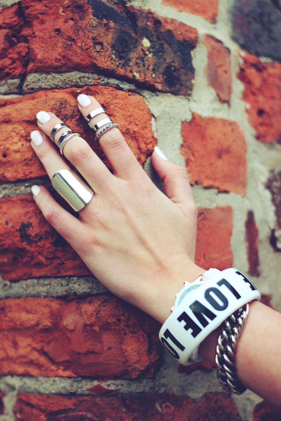 Free Image of Womens Hand With Two Rings on Brick Wall 