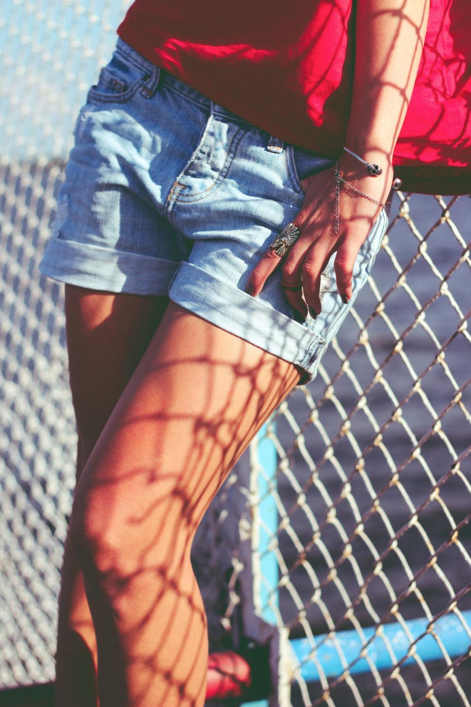 Free Image of Woman Standing Next to Chain Link Fence 