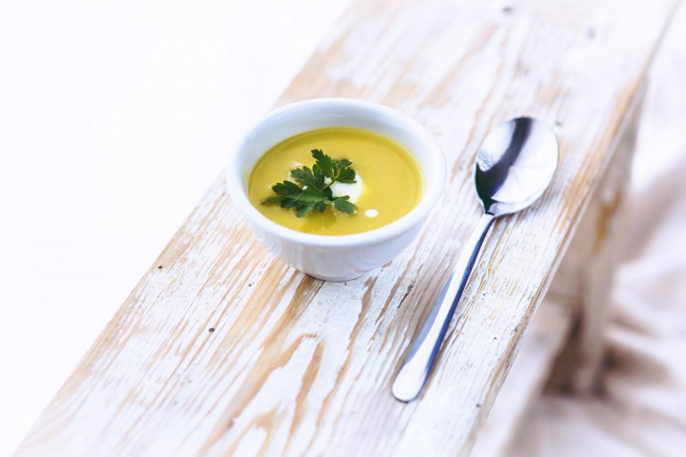 Free Image of A Bowl of Soup With a Spoon on a Wooden Table 