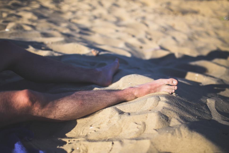 Free Image of Man Laying on Sandy Beach 