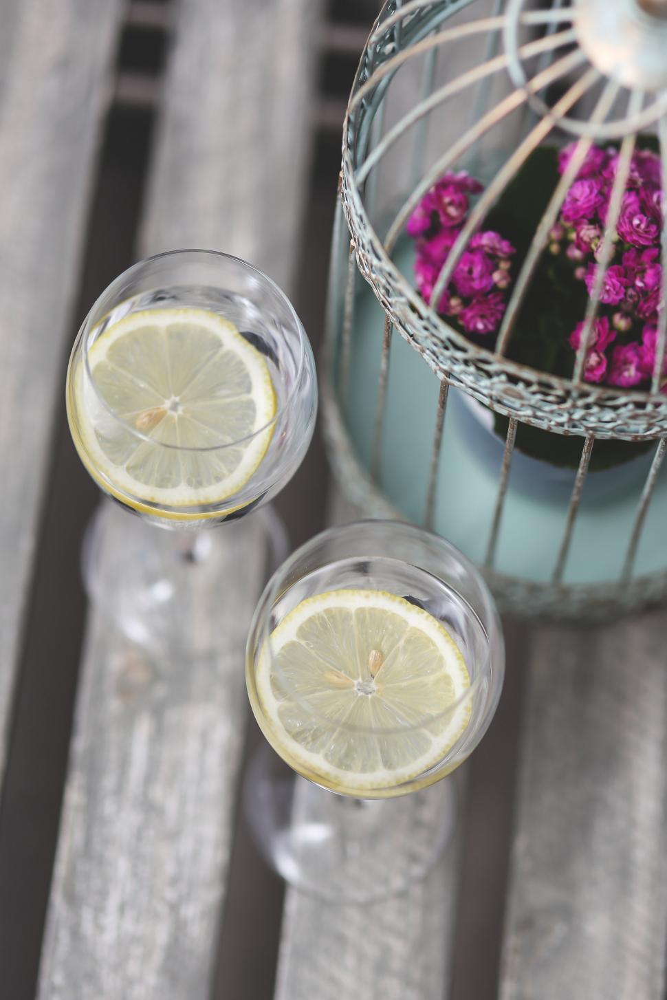 Free Image of Two Glasses of Lemonade With a Birdcage in the Background 