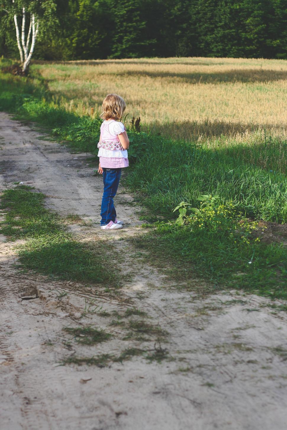 Free Image of A Little Girl Walking Down a Dirt Road 
