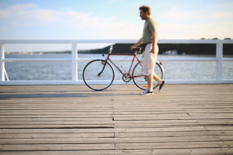 Free Image of Man Riding Bike Across Wooden Bridge 