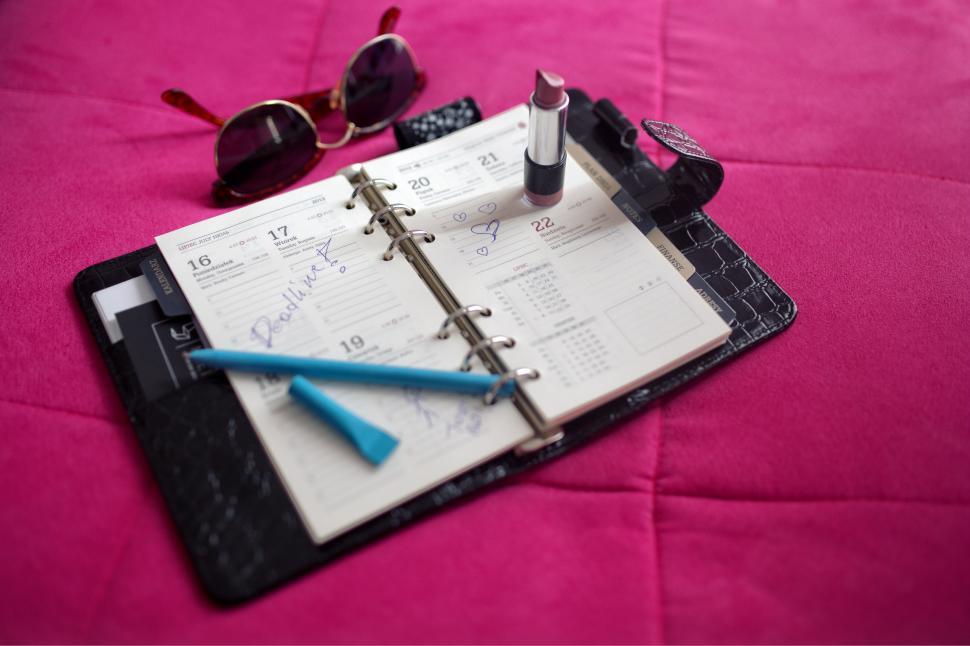 Free Image of Notebook, Sunglasses, and Pen on Bed 