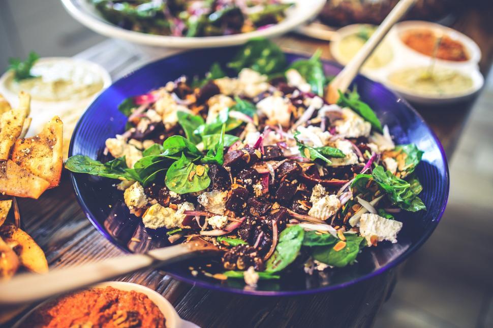 Free Image of Blue Bowl Filled With Salad Next to Plates of Food 