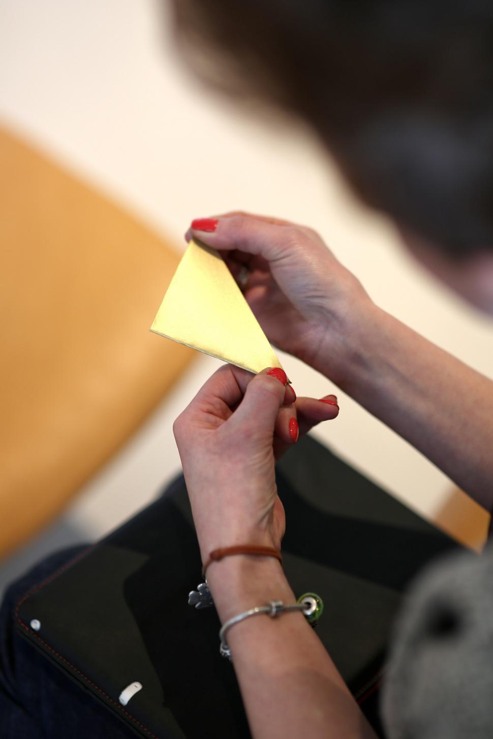 Free Image of Woman Holding a Piece of Yellow Paper 