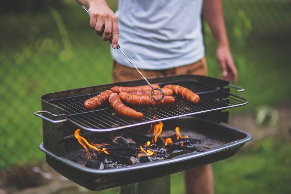 Free Image of Man Cooking Hot Dogs on Grill 