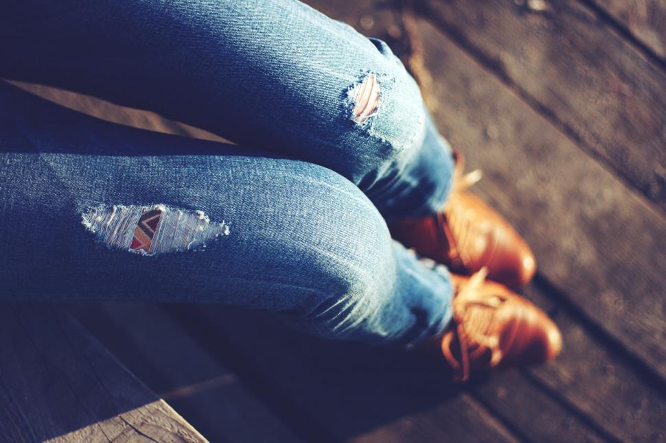 Free Image of Distressed Jeans With Holes Sitting on Bench 