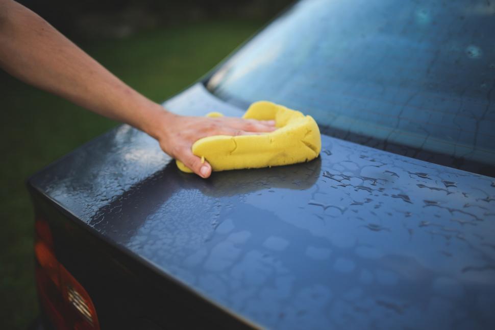 Free Image of Person Cleaning a Blue Car With a Yellow Cloth 