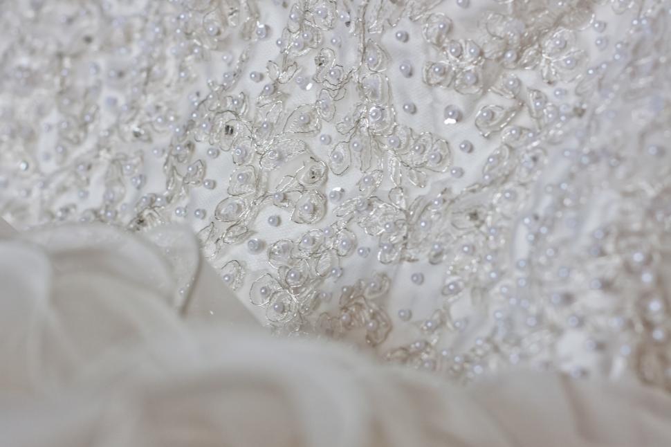 Free Image of Close Up of a Wedding Dress on a Bed 