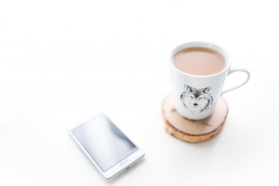 Free Image of Coffee Cup Next to Cell Phone 