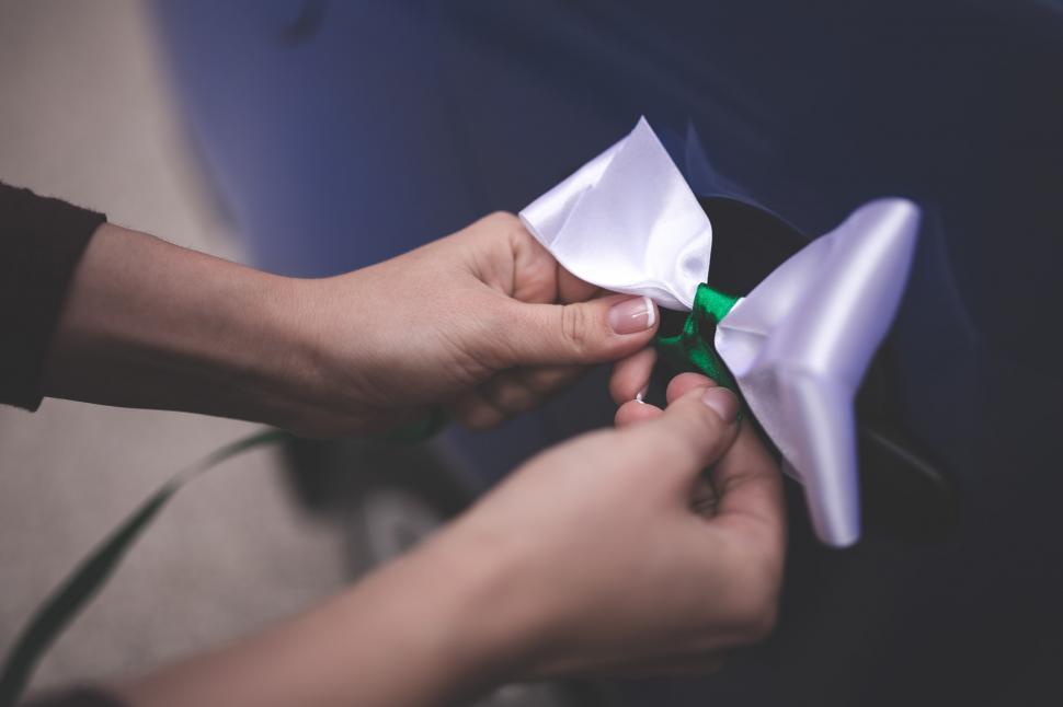 Free Image of Person Tying White Bow With Green Ribbon 