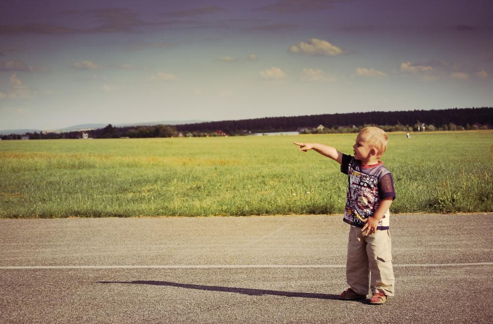 Free Image of Little Boy Pointing at Something on the Side of the Road 