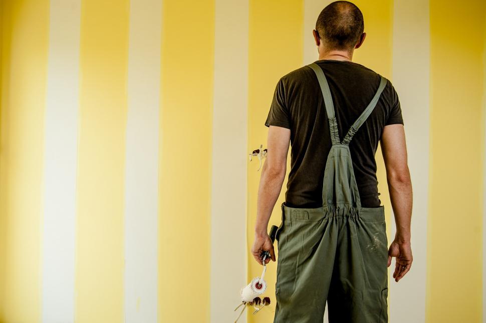 Free Image of Man With Skateboard Standing in Front of Striped Wall 