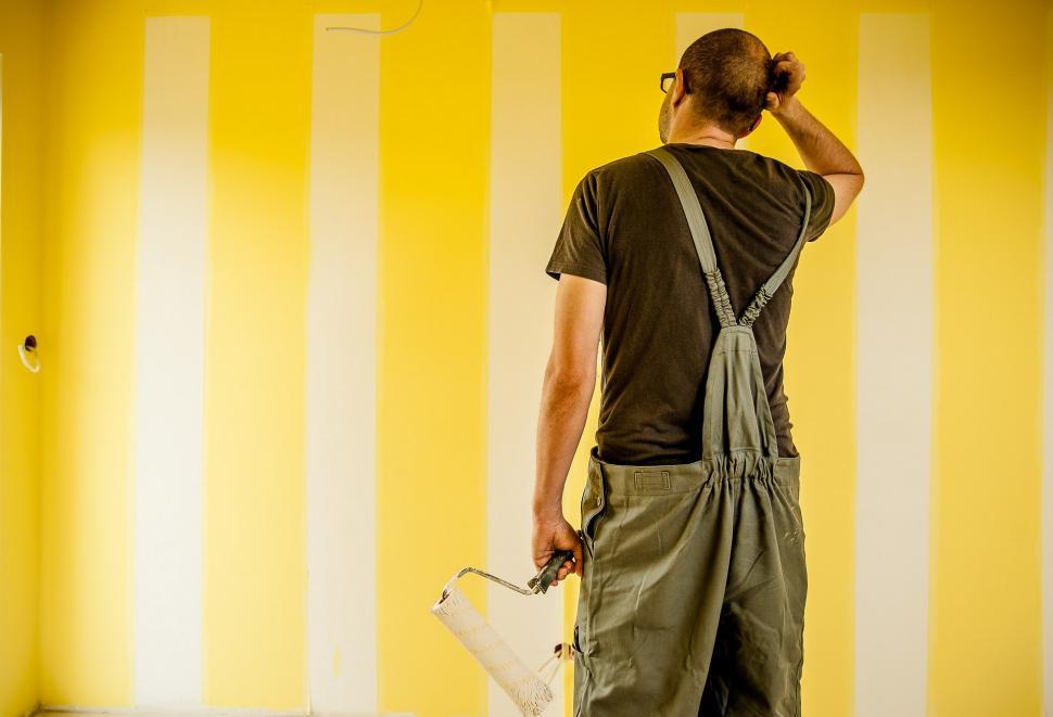 Free Image of Man Painting Wall With Yellow and White Stripes 