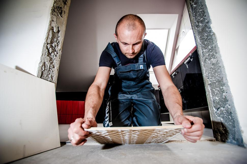 Free Image of Man Wearing Black Shirt and Blue Overalls Working on Wood 