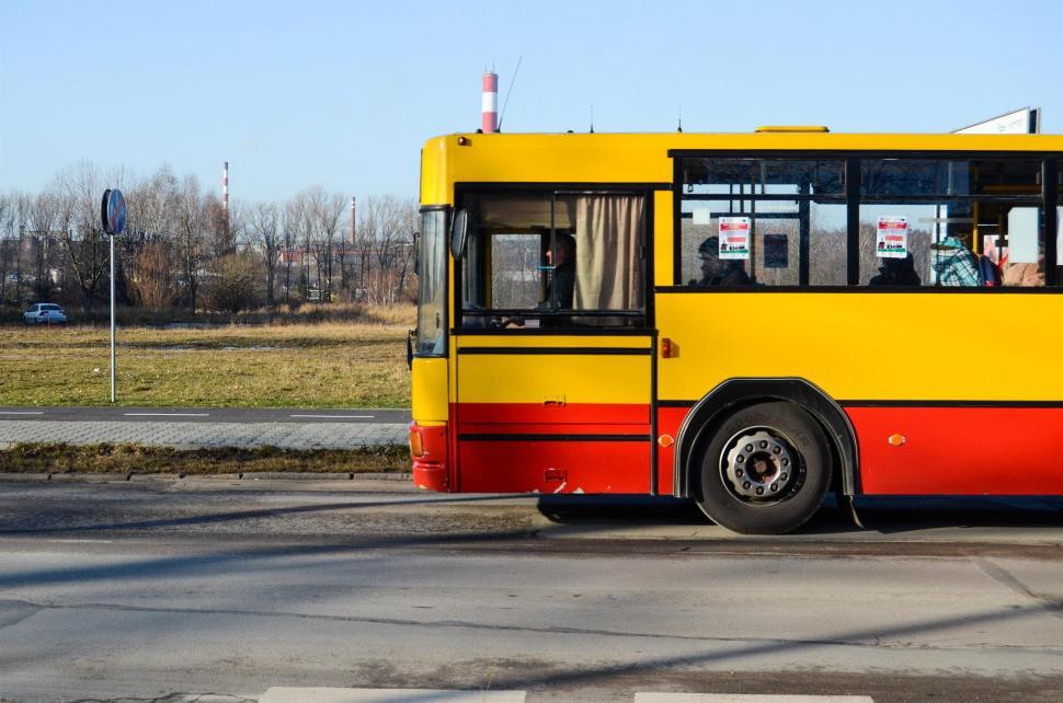 Free Image of Yellow and Red Bus Driving Down Street 