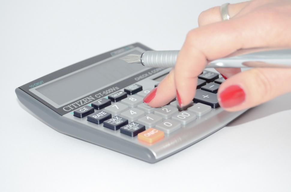 Free Image of Woman Using Calculator on Table 