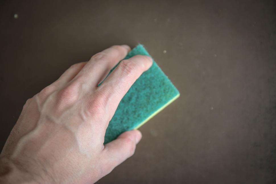 Free Image of Hand Holding Sponge on Black Surface 