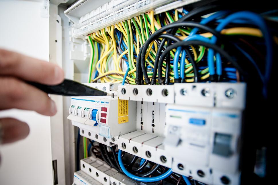 Free Image of Person Holding Remote Control in Front of Rack of Wires 