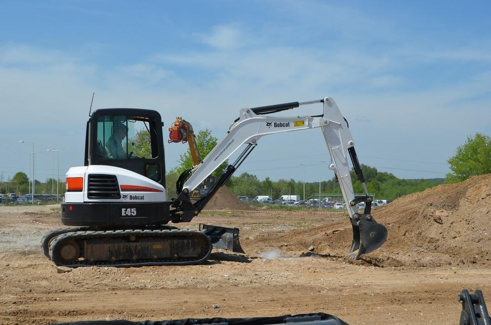 Free Image of White and Black Bulldozer Digging Dirt in Field 