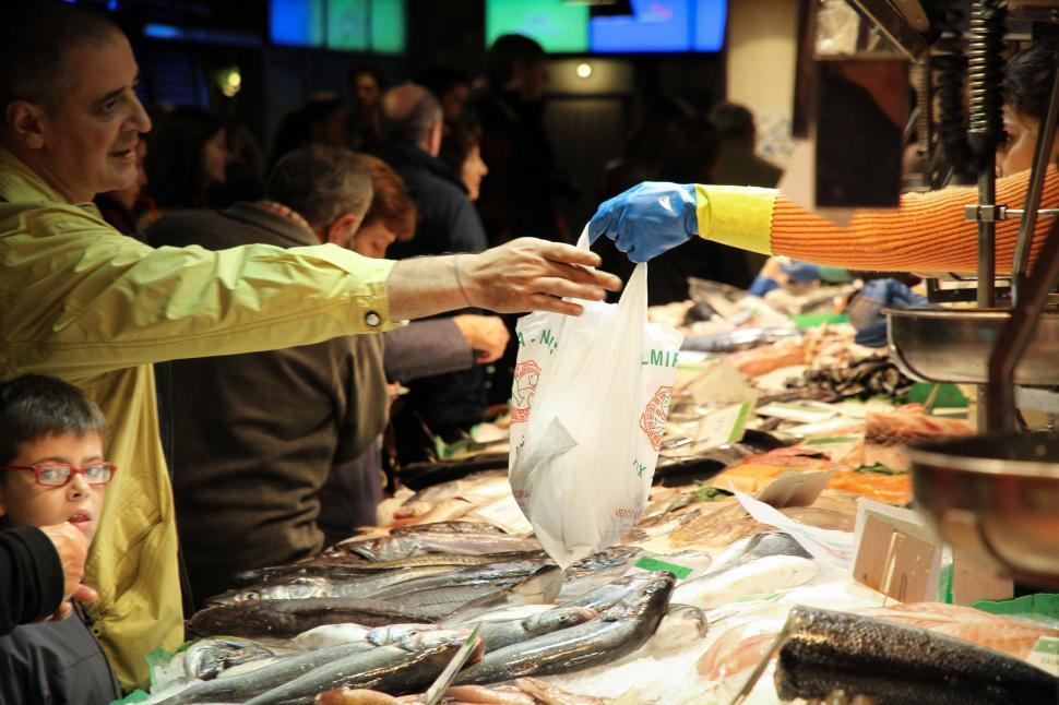 Free Image of Man Handing Bag of Fish to Another Man 
