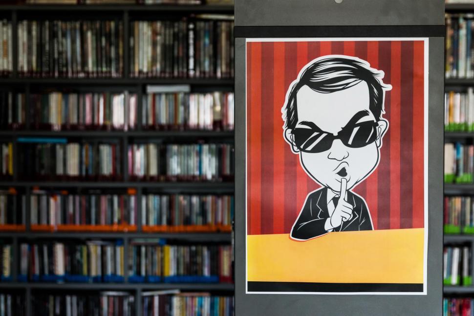 Free Image of Sticker of a Man With Sunglasses on Book Shelf 