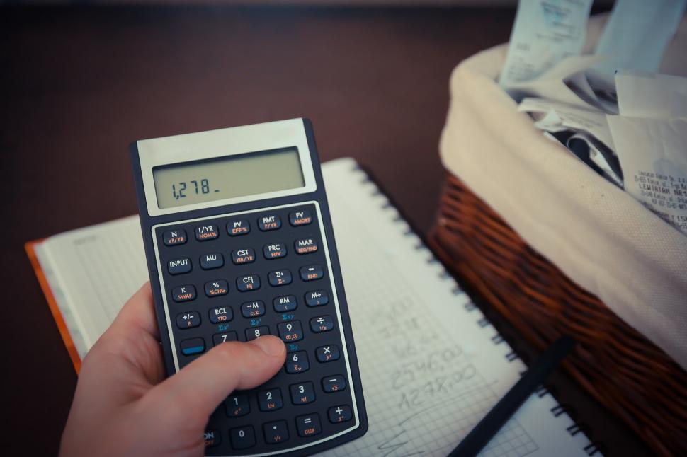 Free Image of Person Calculating Next to Notebook 