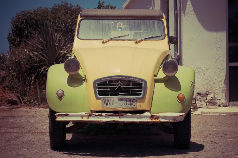 Free Image of Old Yellow Car Parked in Front of Building 