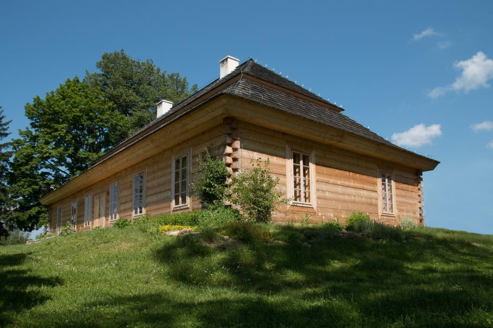 Free Image of Small Log Cabin on Lush Green Hillside 